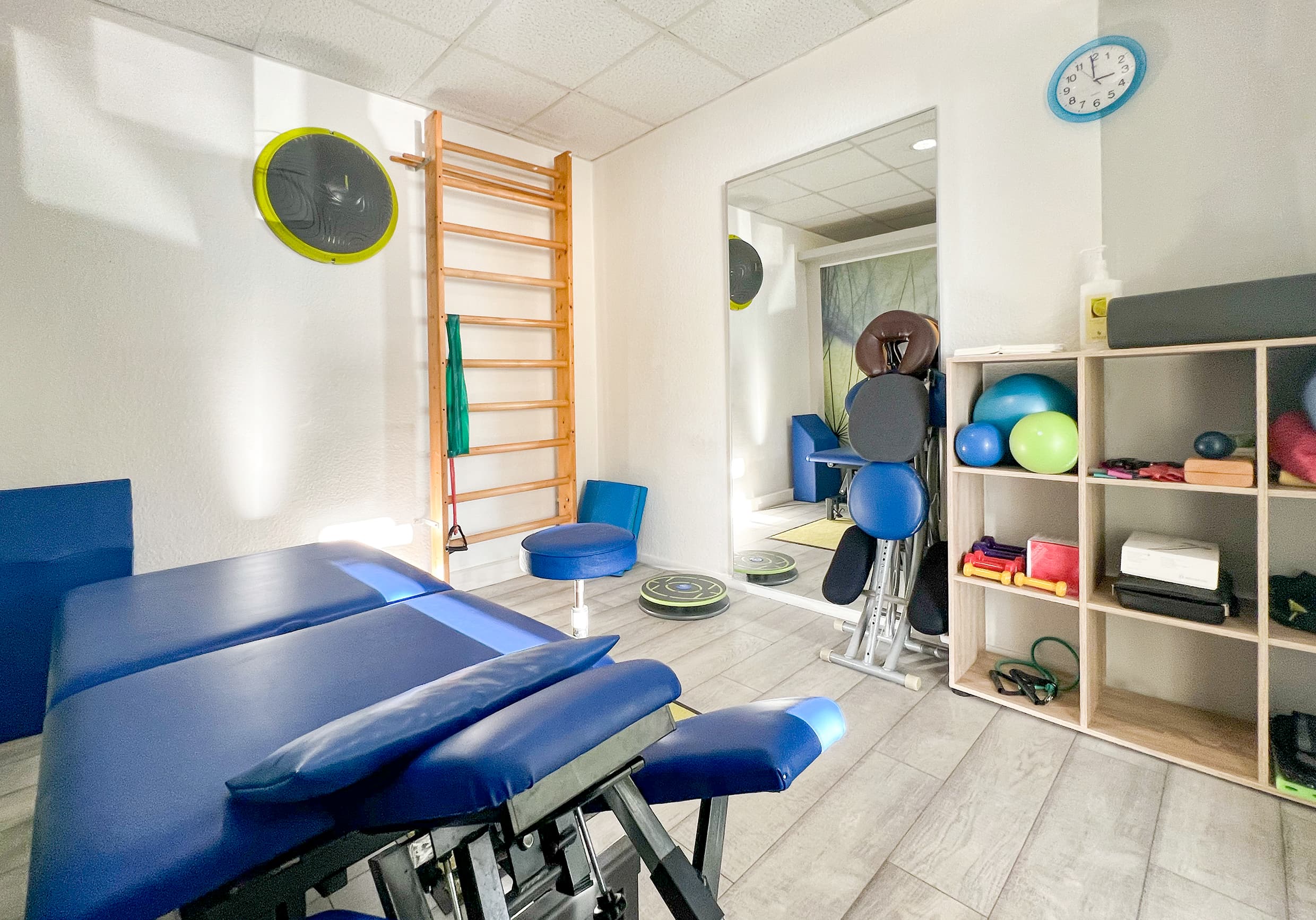 Heller Behandlungsraum mit Therapieliege, Sprossenwand und Trainingsmaterial